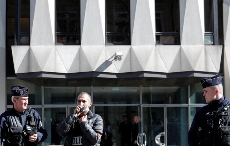 Police officers stand guard in front of the main entrance of the International Monetary Fund (IMF) offices where an envelope exploded in Paris