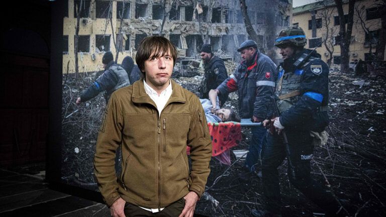 фотограф Євген Малолетка на тлі свого фото з Маріуполя